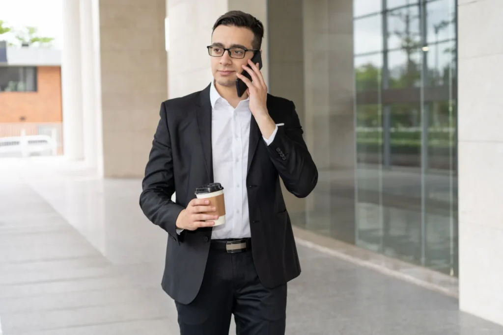A Business man speaking with phone with a cup og coffee